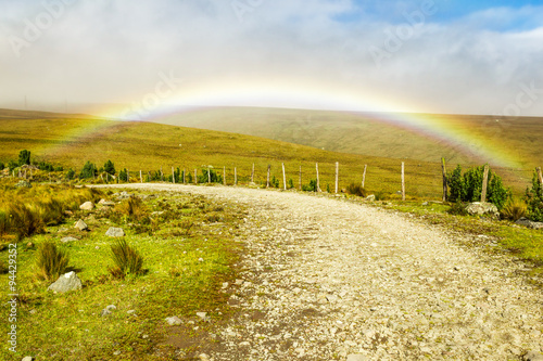 Experience the breathtaking beauty of a high altitude road adorned with a vibrant rainbow,nestled amidst the majestic Andes Mountains.