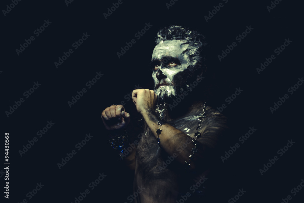 wild man with white painted face and full body black paint