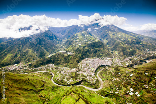 Stunning aerial view of Banos de Agua Santa showcasing the majestic Tungurahua volcano in the backdrop and the picturesque Pastaza river in the foreground. photo