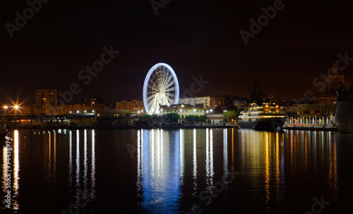 Night lights in the port of Malaga. Ferris wheel in the background. Long exposure.