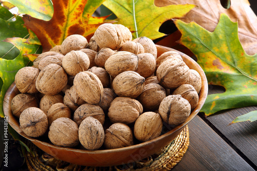 Bowl of walnuts on a wooden background with autumn leaves