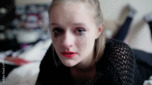 Girl lying on the bed and crying to the camera
