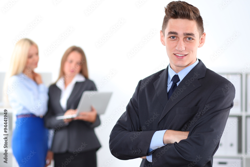 Cheerful business man in office with colleagues in the background, sturt-up team Cheerful business man in office with colleagues in the background, sturt-up team