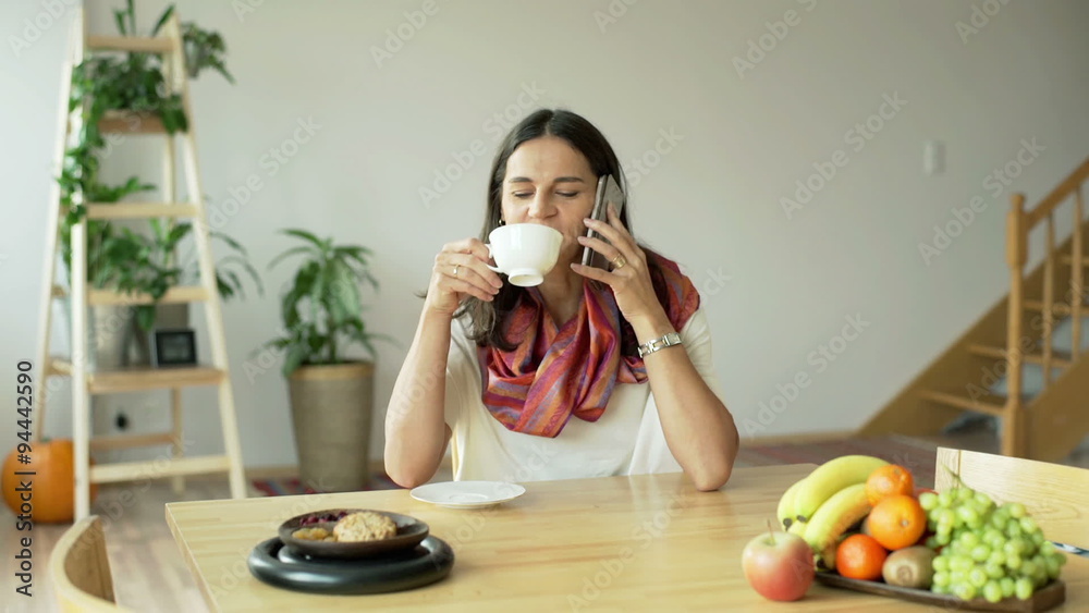 Woman smiling to the camera while drinking coffee and talking on cellphone
Woman smiling to the camera while drinking coffee and talking on cellphone