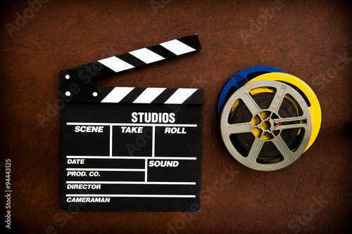 Movie clapper board and film reels on wooden floor