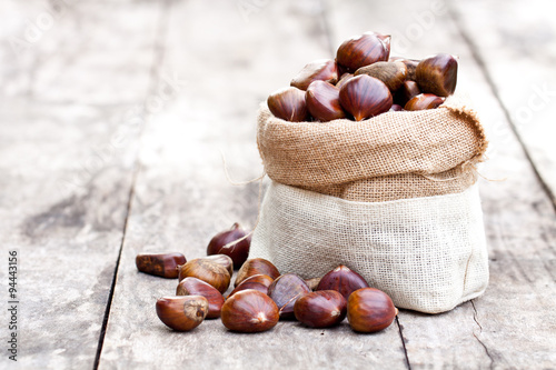 fresh chestnuts in sack bag on the old wooden table photo