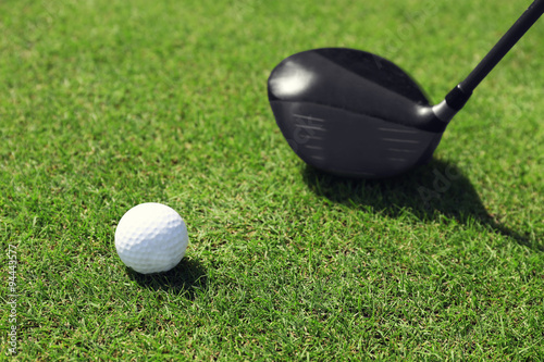 Golf club and ball on a green grass