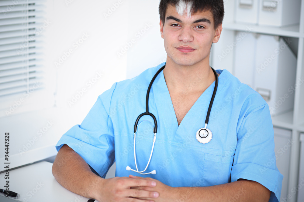 Portrait of unknown male surgeon doctor sitting at the table in hospital office, stethoscope Portrait of unknown male surgeon doctor sitting at the table in hospital office, stethoscope