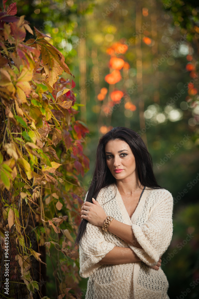 Beautiful woman in white posing in autumnal park. Young brunette woman spending time in autumn near a tree in forest. Long dark hair attractive woman smiling with faded leaves around her Beautiful woman in white posing in autumnal park. Young brunette woman spending time in autumn near a tree in forest. Long dark hair attractive woman smiling with faded leaves around her