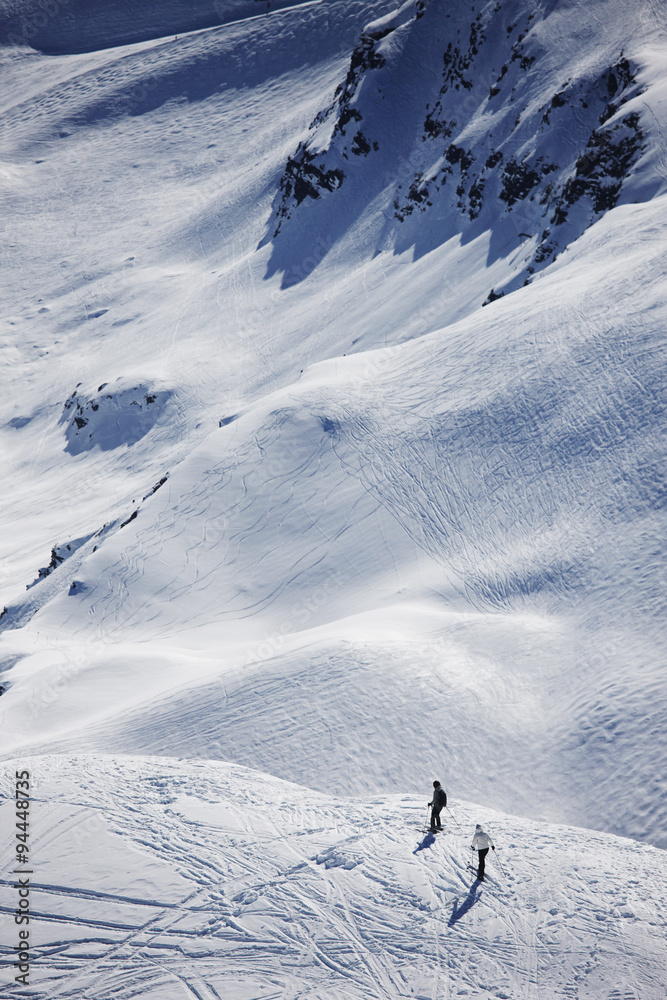 Two skiers going off piste to ski in the three valleys, France.