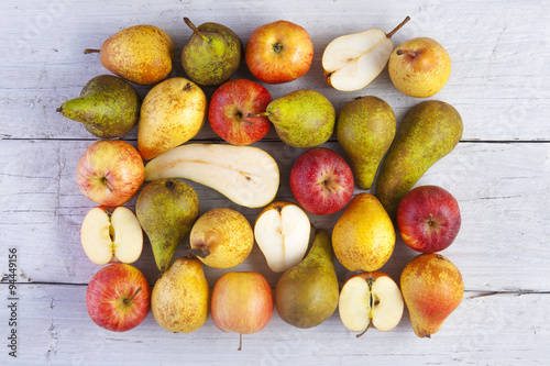 apples and pears whole and halved shot from above on white wooden boards