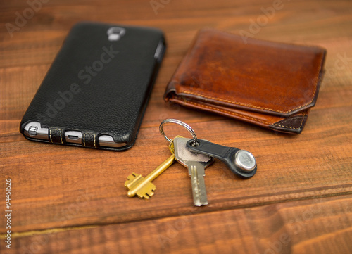 Leather purse, phone pouch and keys on a wooden table background