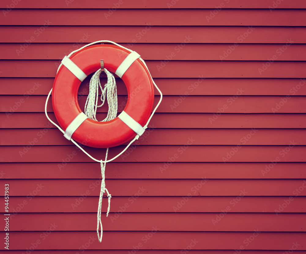 Ring buoy on red wooden wall background