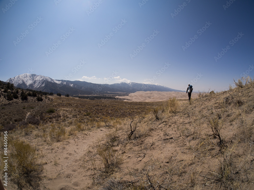 Backpacker Walks Along Sandy Path at Great Sand Dunes National Park Backpacker Walks Along Sandy Path at Great Sand Dunes National Park