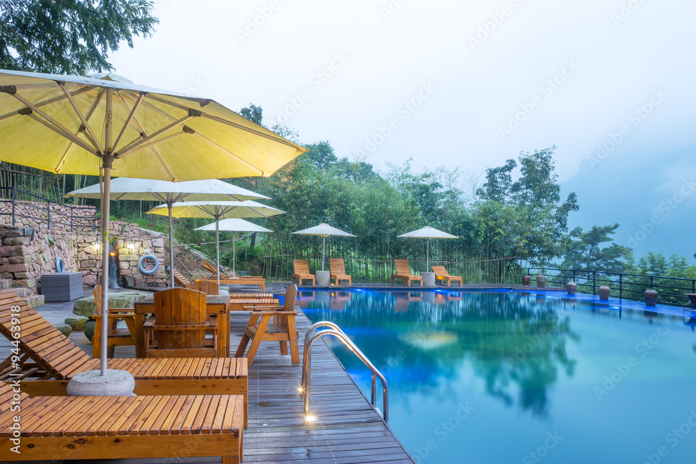 Umbrella chair in hotel pool resort with sunset