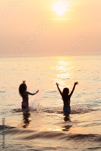 two juvenile girls have fun on the beach at sunset