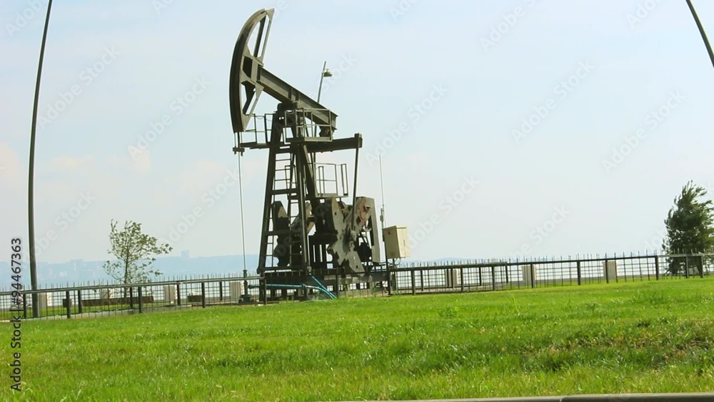 Oil pump and green grass in Baku, Azerbaijan, near the Caspian Sea, with nice sky background and young man with bicycle crossing Oil pump and green grass in Baku, Azerbaijan, near the Caspian Sea, with nice sky background and young man with bicycle crossing