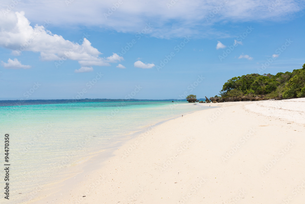 Pristine white tropical beach with blue sea and lush vegetation