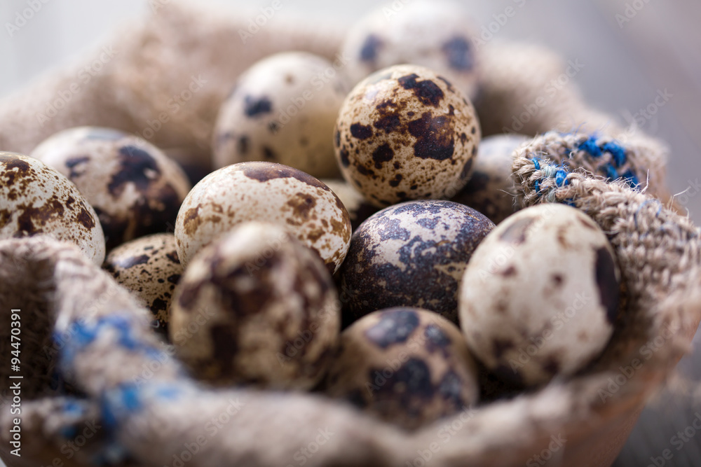 Obraz premium Quail eggs in a wooden bowl on a gray background, close up