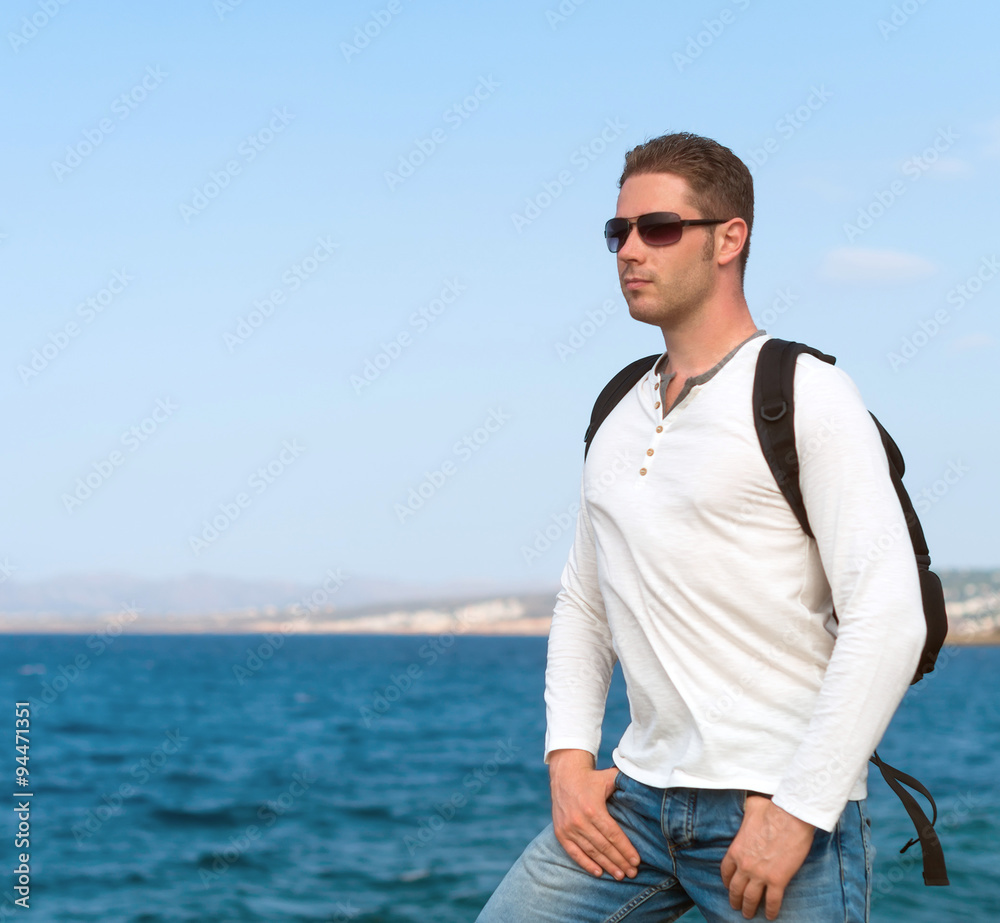 Male tourist with backpack standing near the sea. Male tourist with backpack standing near the sea.