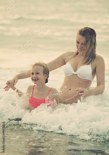 Woman and her daughter having fun in the sea. Vintage effect. © M-Production