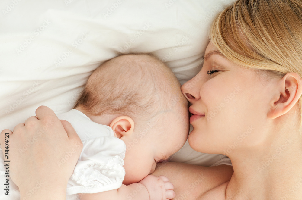 Young mother and her baby, sleeping in bed. Mother and baby. Young mother and her baby, sleeping in bed. Mother and baby.