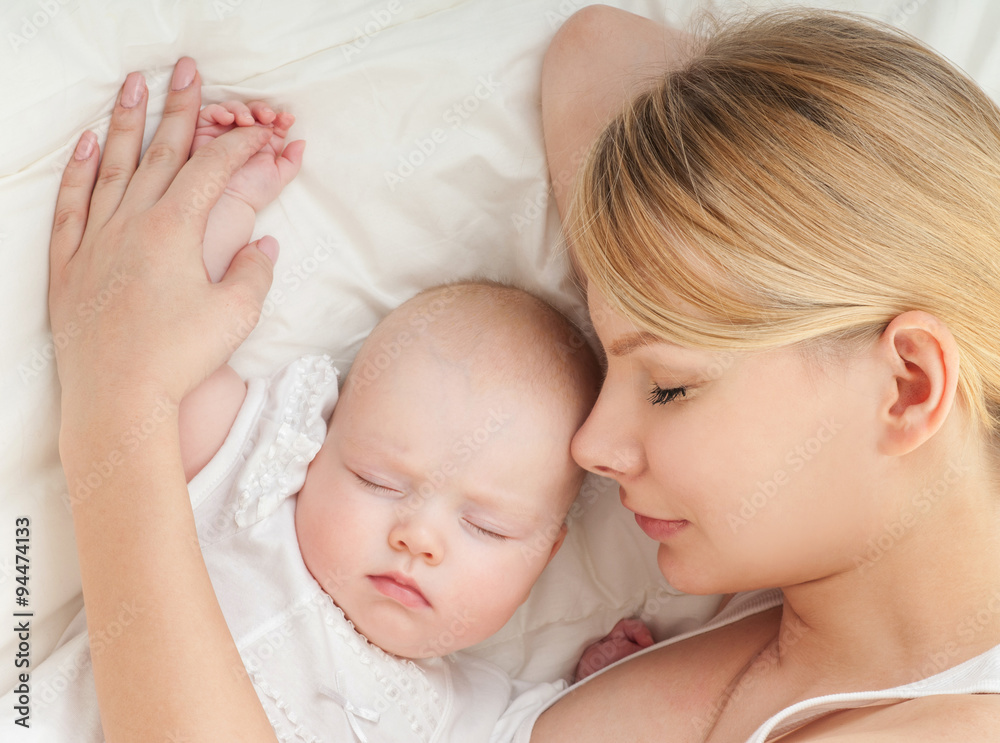 Young mother and her baby, sleeping in bed. Mother and baby. Hap Young mother and her baby, sleeping in bed. Mother and baby. Hap