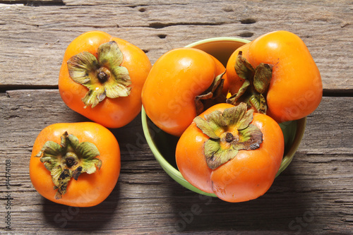 Fresh ripe persimmon on a wooden photo
