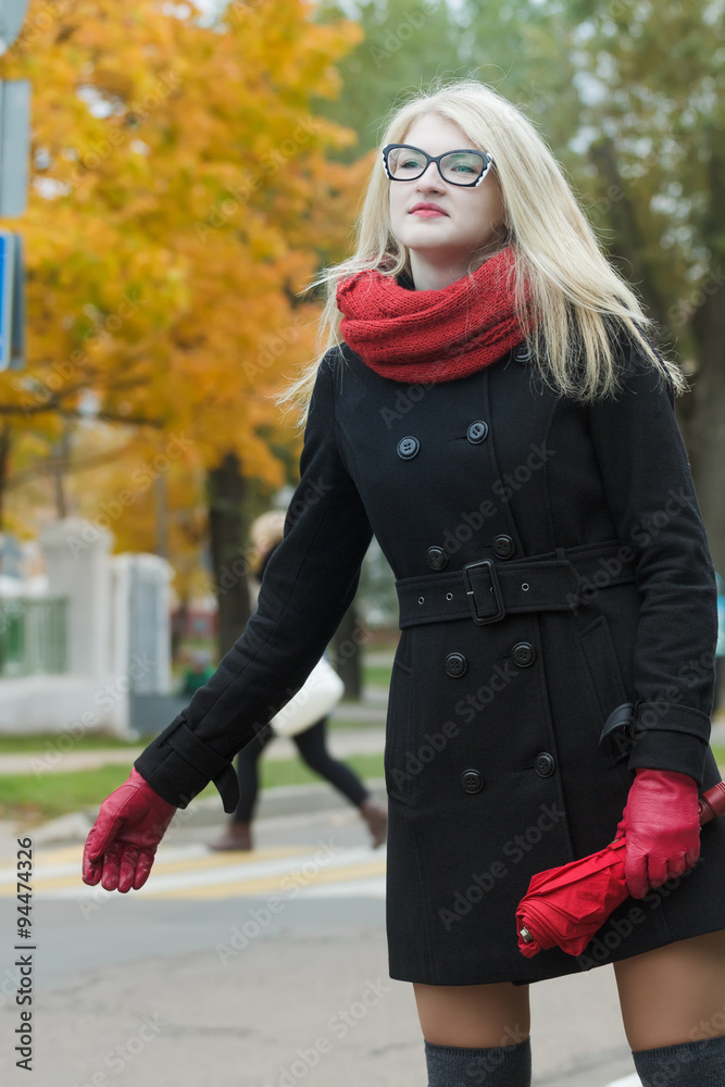 Young woman hailing taxi cab with holding out her one hand with city street at background