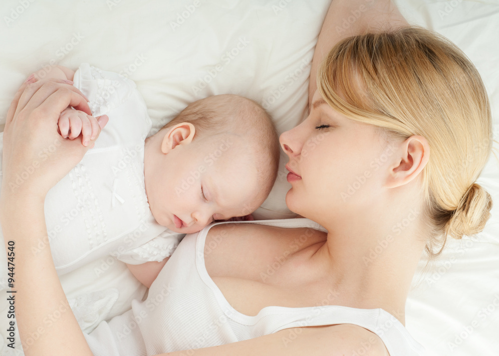 Young mother and her baby, sleeping in bed. Mother and baby. Hap Young mother and her baby, sleeping in bed. Mother and baby. Hap