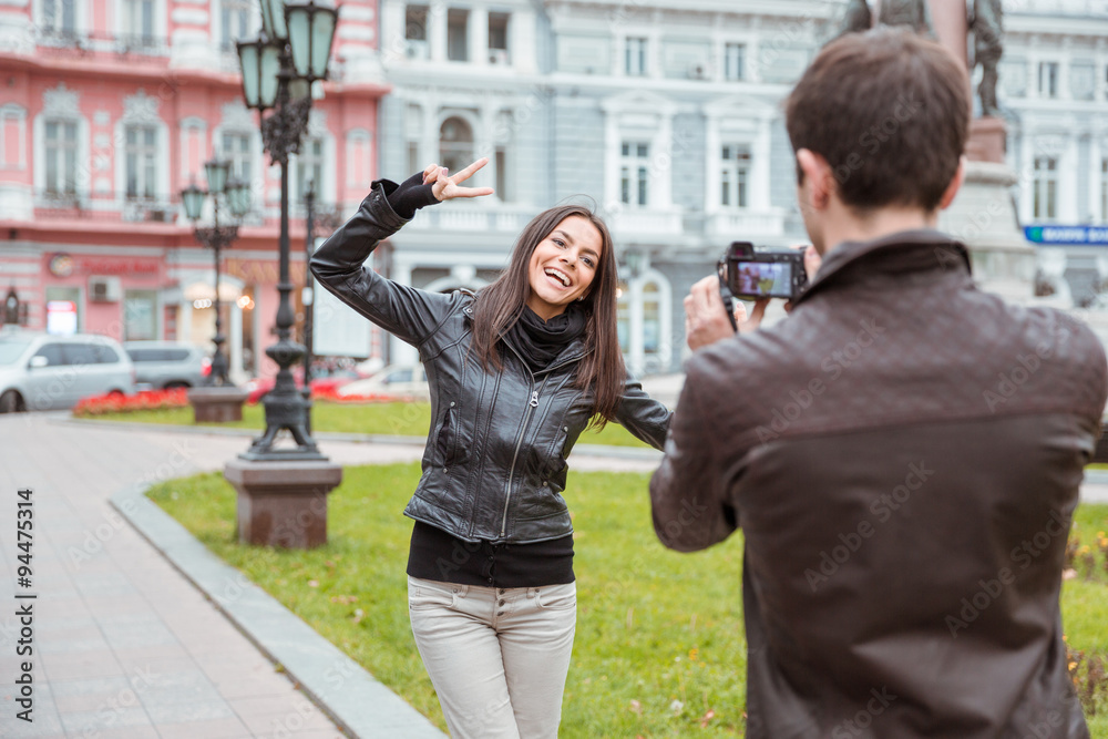 Man making photo of laughing woman outdoors