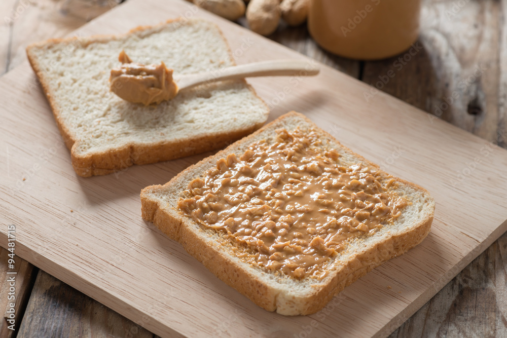 Peanut butter sandwich on wood cutting board.