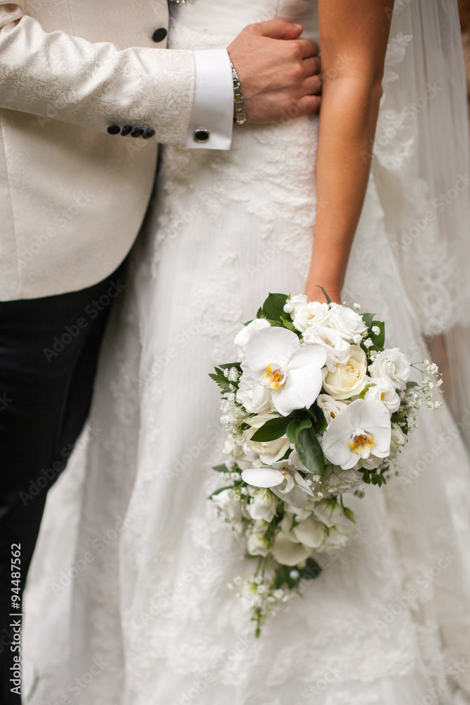 Groom hugs bride who is holding a bouquet Groom hugs bride who is holding a bouquet