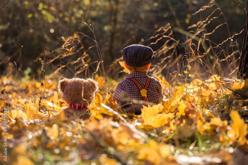 Little boy sitting and playing in autumnal forest. Little boy sitting and playing in autumnal forest.