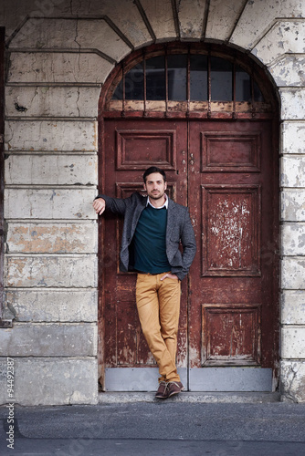 Man in fashionable clothes posing in vintage urban doorway