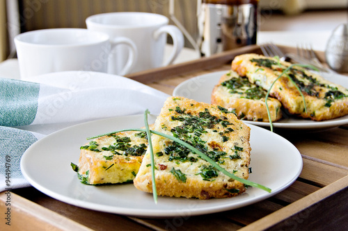Breakfast for two: French toast with fresh herbs and tea on a wooden table