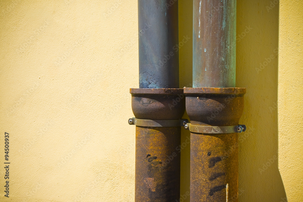 Detail of pair of downpipes copper and cast iron on a colorful facade Detail of pair of downpipes copper and cast iron on a colorful facade