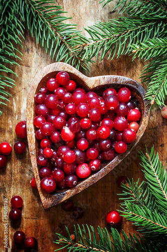 Fresh cranberries in bowl with heart shaped fir paws on the old