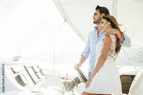 Attractive couple on a yacht enjoy bright sunny day on vacation