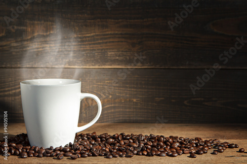 Coffee cup and coffee beans on wooden background.
