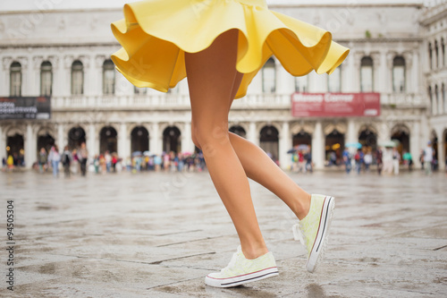 Cheerful young woman wearing sneakers and yellow skirt