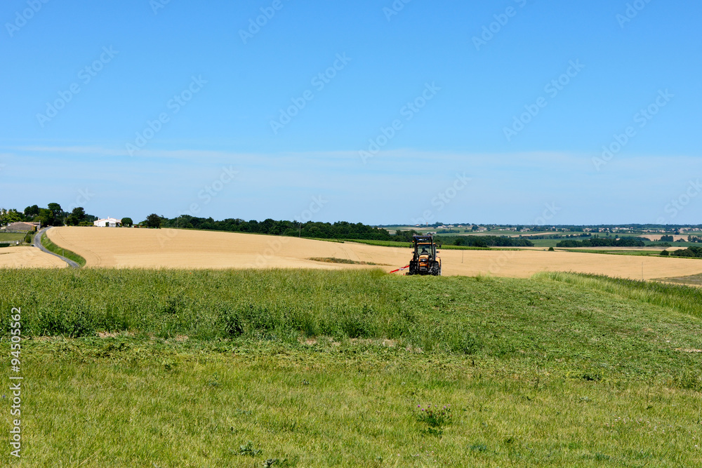 Tractor cutting grass in field in French countryside Tractor cutting grass in field in French countryside