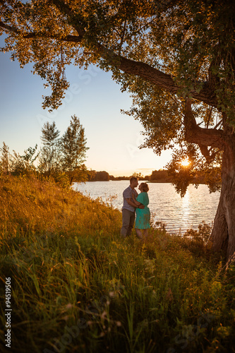 Romantic couple standing and kissing on background summer lake  sunset © ruslan1117
