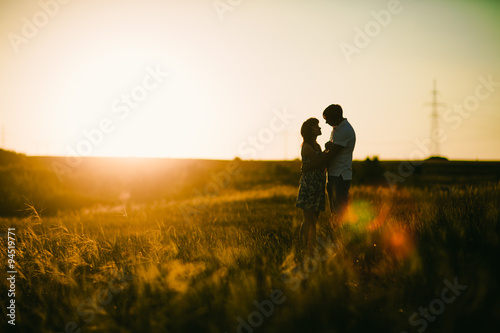 Romantic couple standing and kissing on background summer meadow sunset