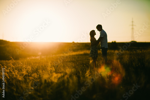 Romantic couple standing and kissing on background summer meadow sunset © ruslan1117