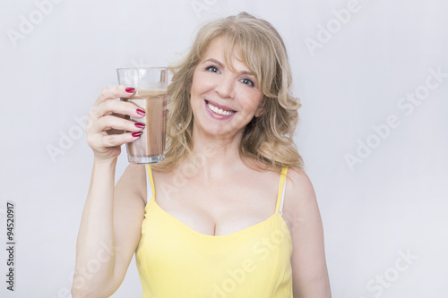 Blonde elder woman showing a glass of hot chocolate 