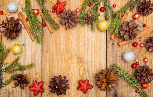 Christmas decoration on rustic wooden desk (pine cones, cinnamon, anise, spruce branches, red stars).