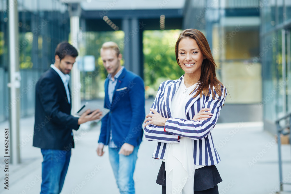 Young businesswoman posing in front of a small group of business Young businesswoman posing in front of a small group of business