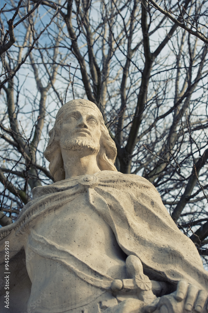 statue's close view behind bare trees in retiro's park in madrid statue's close view behind bare trees in retiro's park in madrid