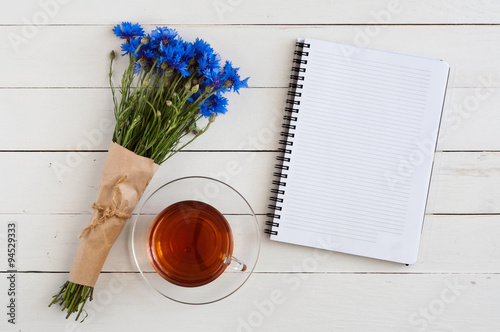 Bouquet of wildflowers with a notepad and a cup tea